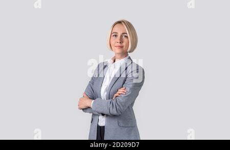 Porträt von seriösen zuversichtlich Business-Dame posiert mit gekreuzten Armen auf hellgrauem Studio-Hintergrund, Panorama Stockfoto