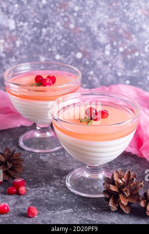 Italienische Dessert Panna Cotta zu weihnachten mit Sahne und Preiselbeere In Glasschalen mit rosa Serviette und Kiefer pürieren Nadeln Stockfoto