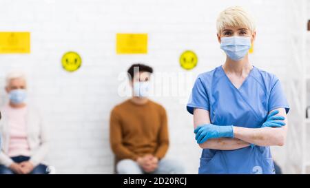 Weibliche Doctor In Face Mask Im Stehen Posiert Im Krankenhaus, Panorama Stockfoto