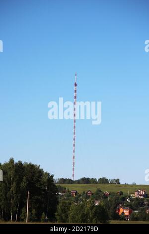 Radio-tv-Turm mit Kabelsalat gegen klaren tiefblauen Himmel, Nahaufnahme. Rot und weiß Gitter Design Stahlstruktur. Stockfoto