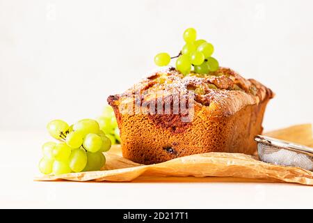 Köstlicher hausgemachter Traubenkuchen mit Thymian und Zuckerpulver auf Pergamentpapier. Heller Steinhintergrund. Stockfoto