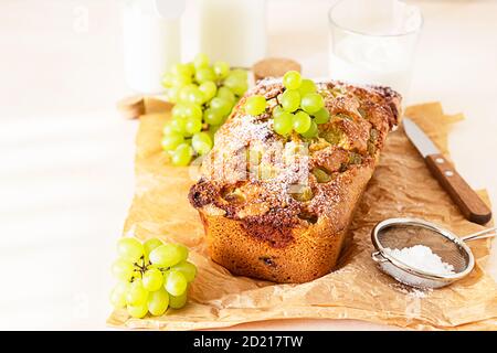 Köstlicher hausgemachter Traubenkuchen mit Thymian und Zuckerpulver auf Pergamentpapier. Heller Steinhintergrund. Stockfoto