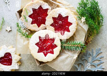 Traditionelle österreichische Kekse mit roter Marmelade. Weihnachten oder Neujahr hausgemachte süße Geschenk in Geschenkbox. Festliche Dekoration. Steinhintergrund. Draufsicht. Stockfoto