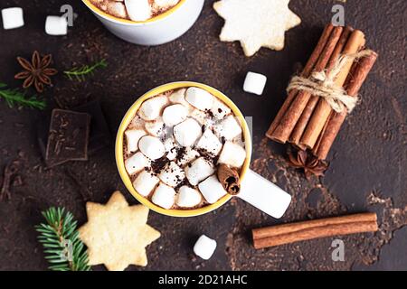 Heiße Schokolade oder Kakao mit Marshmallow und Zimt, Mürbeteiggebraten, Gewürzen und Bitterschokolade auf dunklem Steingrund. Festliche Weihnachten oder Stockfoto