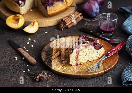 Hausgemachter süßer Pflaumenkuchen oder Kuchen mit Nüssen und Gewürzen auf Holzbrett, dunkelbrauner Steinhintergrund. Obstkuchen. Rustikaler Stil. Stockfoto