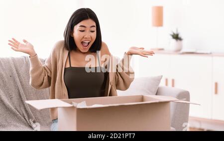 Aufgeregt asiatische Frau Auspacken Paket nach Online-Shopping Stockfoto