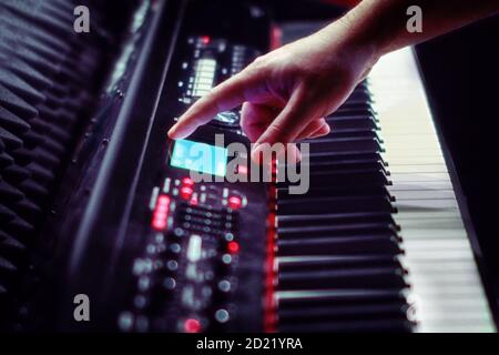 Eine Männerhand zeigt auf der elektronischen Anzeigetafel Klavier Synthesizer steht im Recording Studio. Große weiße und schwarze Tasten Stockfoto