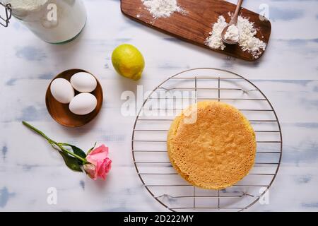 Zutaten für Kuchen Biskuitkuchen mit Zitrone auf weißem Hintergrund, Holztisch und Blume Stockfoto