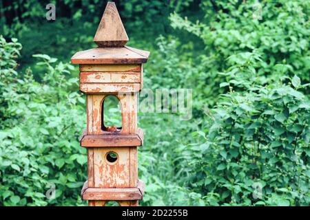 Retro Säule mit Vogelfutterhäuschen und Eichhörnchen im Park. Stockfoto
