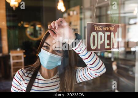 Weibliche Friseur trägt Gesichtsmaske auf dem Glas lehnt Friseursalon Stockfoto
