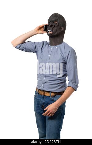 Mann in Gorilla Maske im Gespräch auf Handy. Isolierter Ausschnitt auf weißem Hintergrund. Mittlere Aufnahme. Seitenansicht. Stockfoto