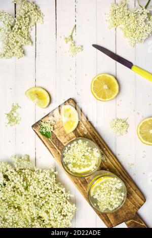 Zwei Gläser selbstgemachte Holunderblütenlimonade und frische Zutaten für einen gesunden und erfrischenden Drink, Draufsicht. Stockfoto