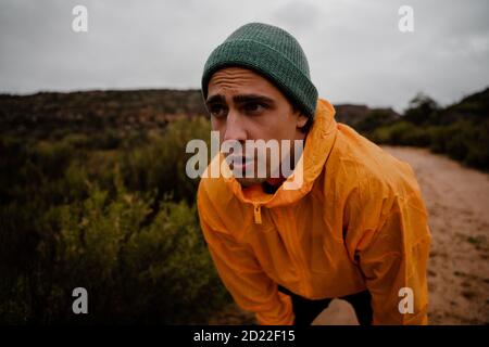 Portrait attraktiver junger Läufer, der sich nach einem schnellen Abfahrtsprint ausruhte Auf Bergpfad bei bewölktem Wetter mit Laub Stockfoto