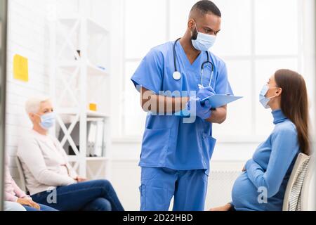 Männlich Krankenschwester Im Gespräch Mit Schwangeren Patienten Frau Im Krankenhaus Stockfoto
