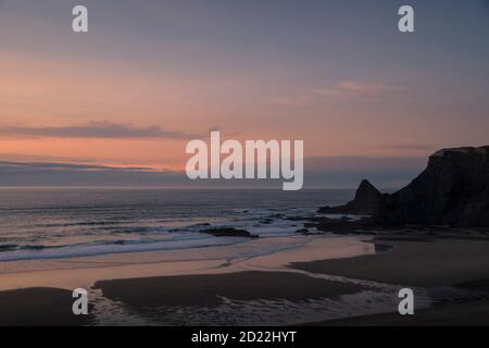 Ozeanlandschaft bei Sonnenuntergang, nachdem die Sonne verschwindet, mit rosa Tönen, mit der Horizontlinie, die den bewölkten Himmel und das Wasser trennt Stockfoto