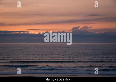 Ozeanlandschaft bei Sonnenuntergang, nachdem die Sonne verschwindet, mit rosa Tönen, mit der Horizontlinie, die den bewölkten Himmel und das Wasser trennt Stockfoto