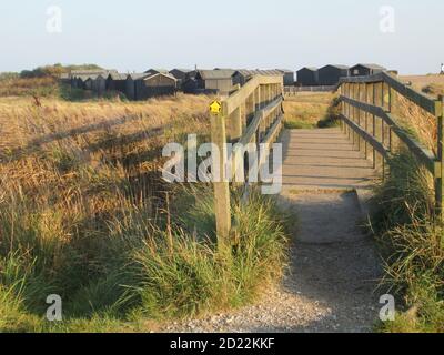 Sommerlandschaft in Walberswick bei Southwold in Suffolk East Anglia von der Holzbrücke zum Campingplatz steiniger Strand & Hütten auf Sanddünen Stockfoto