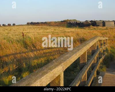 Sommerlandschaft in Walberswick bei Southwold in Suffolk East Anglia von der Holzbrücke zum Campingplatz steiniger Strand & Hütten auf Sanddünen Stockfoto