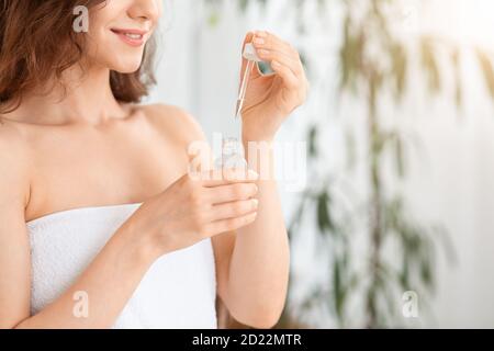 Flasche mit Gesichtsserum in den Händen der jungen Frau Stockfoto