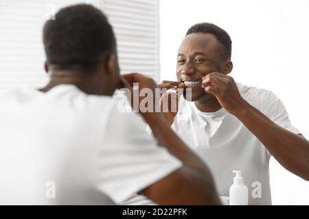 Schwarzer Mann Reinigung Zähne Mit Floss Im Badezimmer Zu Hause Stockfoto