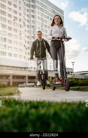 Junger Mann Reiten Einrad und junge Frau in Freizeitkleidung Reiten auf Elektro-Kick Scooter auf City Street Stockfoto