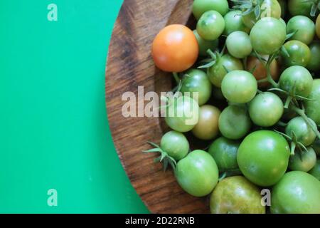 Nahaufnahme Tomaten, frische reife saftige Früchte aus Bio-Garten in Holz Handwerk Schale Innenaufnahme vor lebendigen grünen Kontrast Hintergrund geerntet Stockfoto