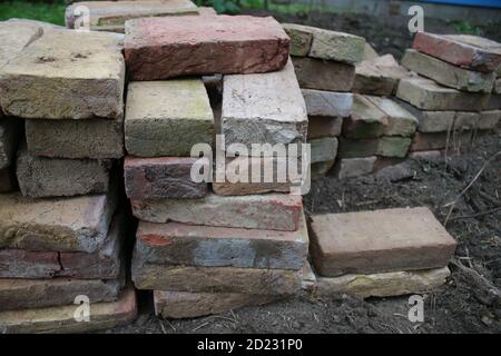 Nahaufnahme des Stapels von alten Lehm zurückgewonnenen Ziegel, jedes längliche Rechteck von Hand gefertigt und aus dem Gebäude zu wiederverwenden, um Gartenweg durch Rasen zu legen gerettet Stockfoto