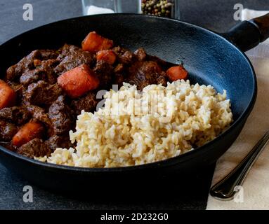 italienisches geschmortes Rindfleisch mit braunem Reis in einer rustikalen Pfanne Stockfoto