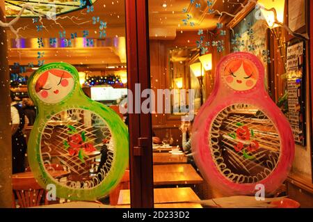 PARIS, FRANKREICH - 27. DEZEMBER 2015: Pariser Café Vitrine zu Weihnachten mit bunten Matryoshka Puppen und Schneeflocken geschmückt. Stockfoto