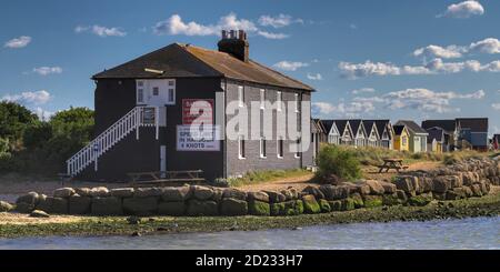 Schwarzes Haus Auf Mudeford Sand Spit Mit Strandhütten In Hintergrund aus Mudeford Quay UK Stockfoto