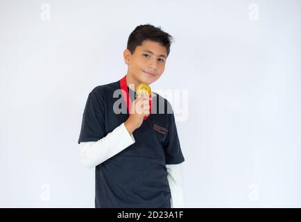 Glücklicher kleiner Junge mit goldener Medaille auf weißem Hintergrund Stockfoto