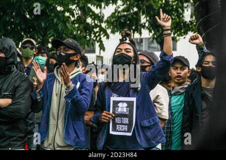 Bandung, Indonesien. Oktober 2020. Ein Protestler macht eine Geste, während er während des Protestes ein Plakat hält, das seine Meinung vor dem Parlamentsbüro ausdrückt. Studenten protestierten gegen den Omnibus-Gesetzentwurf der Regierung zur Schaffung von Arbeitsplätzen, der das Wirtschaftswachstum ankurbeln und Arbeitsplätze schaffen sollte, was ihrer Meinung nach die Arbeitnehmer ihrer Rechte berauben und die Umwelt in Indonesien untergraben würde. Kredit: SOPA Images Limited/Alamy Live Nachrichten Stockfoto