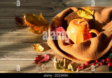 Komposition mit orange Kürbis gestylt Tasse Kaffee und Herbst themed Dekoration, gefallene Blätter, kuschelige Pullover auf braunem Holzhintergrund. Copy Raum. Stockfoto