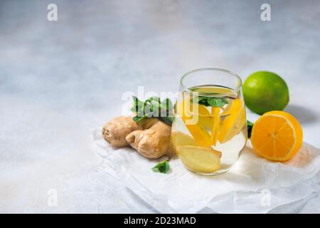 Ingwer-Zitrone-Getränk. Hausgemachter Bio-Ingwer in einem Glas mit Zitrone und Minze auf weißem Tisch. Trendige Detox gesundes Getränk. Stockfoto