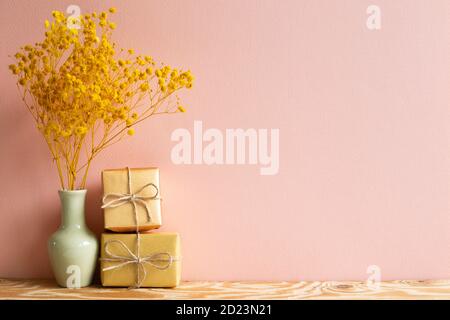 Geschenkkartons mit gelbem Baby Atem, Gypsophila trockene Blumen auf Holztisch mit rosa Hintergrund Stockfoto