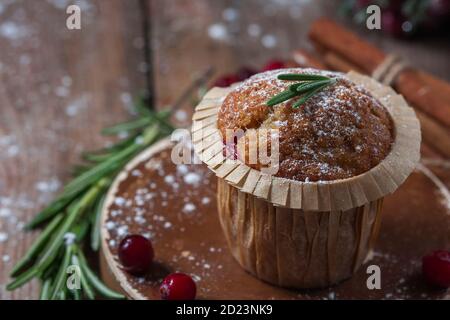 Frische hausgemachte Cranberry Muffins in Backform auf Holztisch mit weihnachtlicher Dekoration. Muffins in umweltfreundlicher, recycelbarer Papierverpackung. Stockfoto