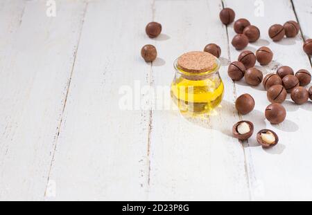 Natürliches Macadamiaöl und Macadamianüsse auf weißem Holzbrett. Gesundes Produkt. Gesunde Ernährung Konzept. Stockfoto