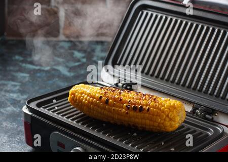 Köstlicher gebratener Mais auf einem kleinen hausgemachten Grill. Gegrilltes Gemüse, vegetarisches Essen. Stockfoto