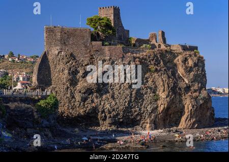 Die 1076 gegründete normannische Burg Castello di Aci oder Castello Normanno in Aci Castello, Provinz Catania, Sizilien, Italien. Die Burg wurde auf einem Basaltstreifen gebaut, der bei einem Unterwasserausbruch hinterlassen wurde, und überblickt Inseln, die einst als Raketen galten, die vom Zyklopen auf den Fluchtheld Odysseus geschleudert wurden. Heute ein beliebtes Touristenresort an der Riviera dei Ciclopi, es gibt häufig Badende auf Felsen am Fuße des Burgzapfens. Stockfoto