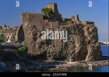 Die Burg wurde 1076 gegründet, das normannische Castello di ACI oder Castello Normanno in ACI Castello, Provinz Catania, Sizilien. Die Burg wurde auf einem Basaltfelsen errichtet, der durch eine Unterwasserausbrüche hinterlassen wurde und überblickt Inseln, von denen einst vermutet wurde, dass sie Raketen waren, die von Zyklopen auf den fliehenden Helden Odysseus geschleudert wurden. Heute ist es ein beliebter Ferienort an der Riviera dei Ciclopi, wo sich am Fuße des Burgfelsens häufig Badende auf Felsen befinden. Stockfoto