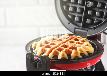 Der Prozess der Herstellung von hausgemachten Waffeln. Frisch gebackene Waffeln in einem Waffeleisen. Stockfoto