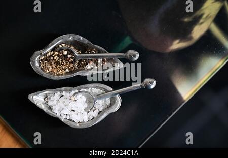 Salz- und Pfeffertöpfe mit kleinen Löffeln für Geschmack und Aroma Stockfoto