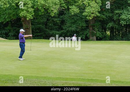 Ein Golfer hält seinen Golfschläger vor sich, um sich auf das Grün im Pinner Hill Golf Club, Pinner, Middlesex vorzubereiten. Stockfoto