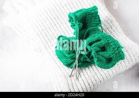 Grünes Strickgarn und Stricknadeln aus nächster Nähe. Stockfoto