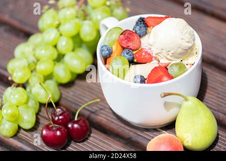 Schüssel mit gesunden frischen Obstsalat mit Eis auf dem Holzhintergrund. Stockfoto
