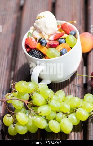 Schüssel mit gesunden frischen Obstsalat mit Eis auf dem Holzhintergrund. Stockfoto