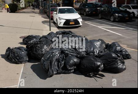 Ein Stapel voller Plastikmüllbeutel, die auf einem sitzen Straßenecke in New york wartet auf Abholung Stockfoto