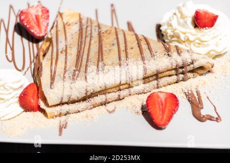 Köstlicher Pfannkuchen mit Erdbeere und Sahne auf dem Teller Stockfoto
