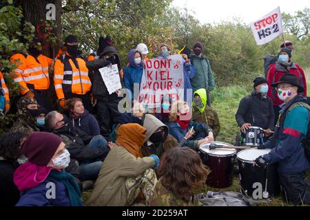 Warwickshire, Großbritannien. Oktober 2020. HS2 Demonstranten brechen durch Barikaden, um auf die Zerstörung eines 250 Jahre alten Baumes aus dem Jahr 2015, des Cubbington Birnenbaums, aufmerksam zu machen 05 Oct 2020. Demonstranten sitzen zu Füßen der HS2-Sicherheitskräfte und halten eine friedliche Mahnwache ab, während die Sicherheitskräfte vor dem Birnenbaum stehen und die Demonstranten davor schwärzen, sich ihm zu nähern.Quelle: Denise Laura Baker/Alamy Live News Stockfoto