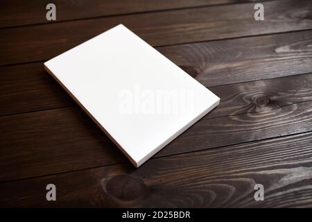 Weiße leere Leinwand auf braunem Holzhintergrund. Modell Stockfoto